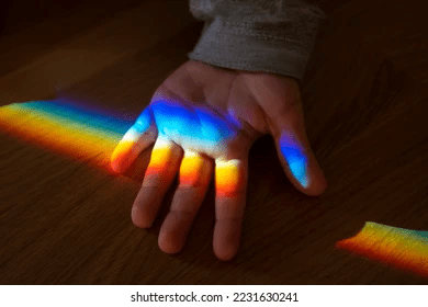 a picture of a person's hand illuminated by a prism of colorful light